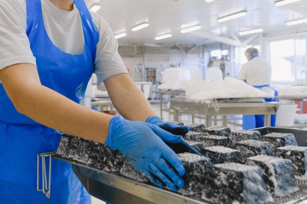 Workers in a sterile environment handling cheese, focused on hygiene and quality control.